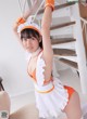 A woman in an orange and white maid outfit posing for a picture.