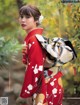 A woman in a red kimono standing in a forest.