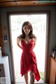 A woman in a red dress standing in front of a door.