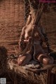 A naked woman sitting on a pile of hay.