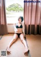 A woman in a black bikini sitting on a tatami mat.