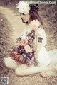 A woman sitting on the ground holding a bouquet of flowers.