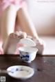 A woman sitting on a table holding a cup and saucer.