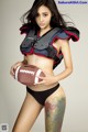 A woman in a football uniform holding a football.