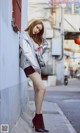 A woman leaning against a wall in a silver jacket.