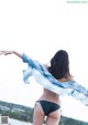 A woman in a black bikini and a blue and white shirt.