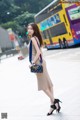 A woman in a beige dress is walking down the street.