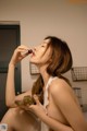 A woman sitting on a bed eating a bowl of fruit.