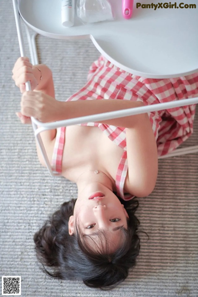 A woman in a red and white checkered dress laying on the floor.