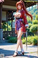 A woman in traditional attire holds a sword, standing outdoors with cherry blossoms.