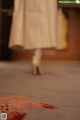 A woman in a white dress walking down a carpeted floor.