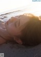 A woman laying on the beach with her eyes closed.