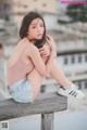 A woman sitting on top of a wooden bench.