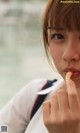 A young woman eating a piece of food by the water.