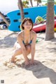 A woman in a blue bikini crouching down on the beach.