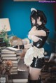 A woman in a black and white dress standing next to a pile of books.