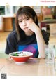 A woman sitting at a table with a bowl of food.