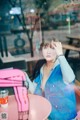 A woman sitting at a table with a pink chair.