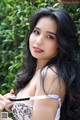 A woman with long black hair wearing a white bra.