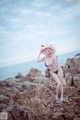 A woman in a bikini standing on a rocky beach.