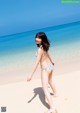 A woman in a bikini walking on the beach.