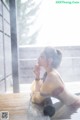 A woman sitting in a bathtub in the rain.