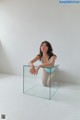 A woman sitting on top of a glass cube.