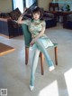 A woman sitting on a chair holding a fan.