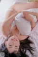 A woman laying on top of a bed in a white underwear.