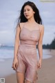 A woman in a pink dress standing on a beach.