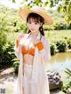 A woman in a white robe and a straw hat posing for a picture.